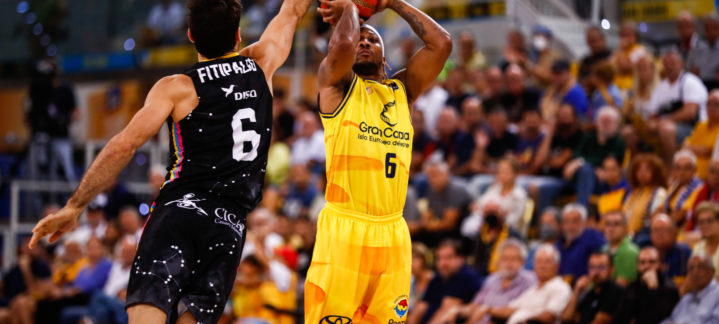 Jugador del Gran Canaria lanzando a canasta mientras es defendido por un oponente.