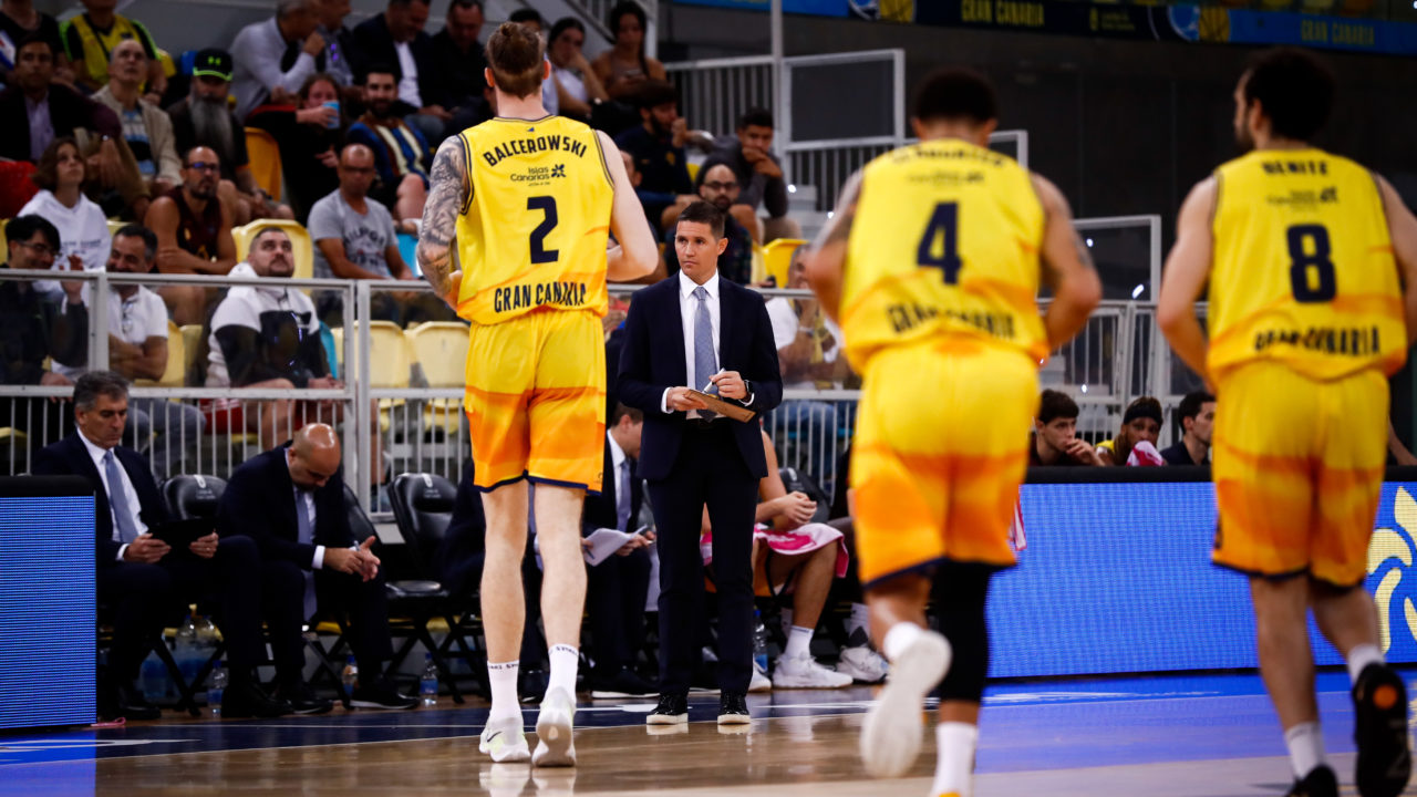 Jugadores del Gran Canaria en un partido, con un entrenador dando instrucciones.