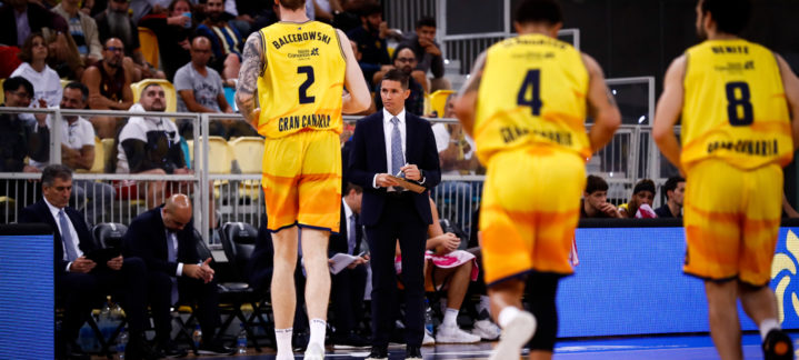 Jugadores del Gran Canaria en un partido, con un entrenador dando instrucciones.