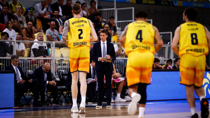 Jugadores del Gran Canaria en un partido, con un entrenador dando instrucciones.