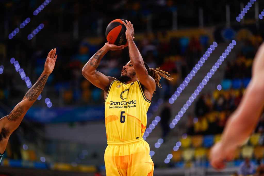Jugador del Gran Canaria lanzando el balón a canasta durante un partido en casa.