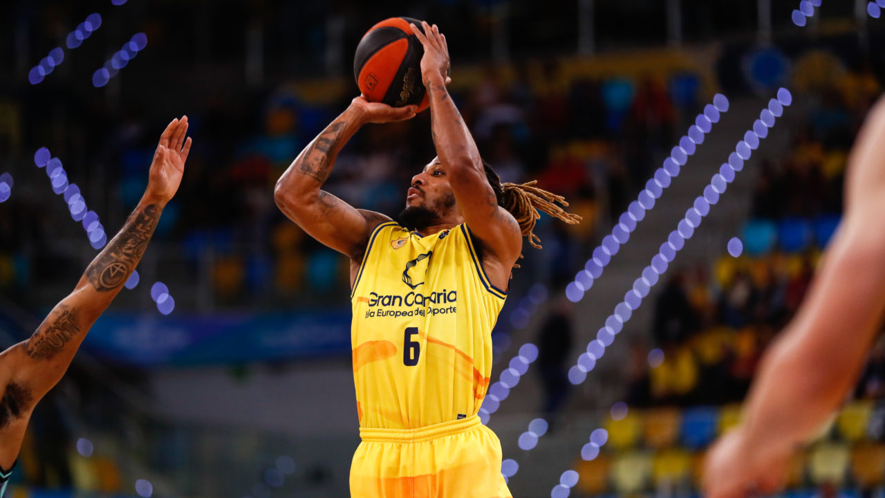 Jugador del Gran Canaria lanzando el balón a canasta durante un partido en casa.