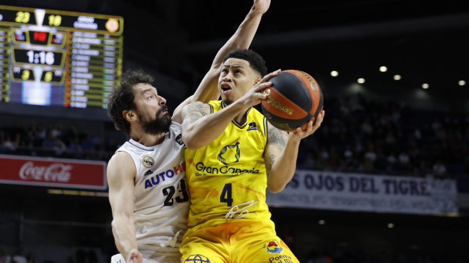 Jugador del Gran Canaria intenta anotar mientras es defendido por un rival del Madrid.