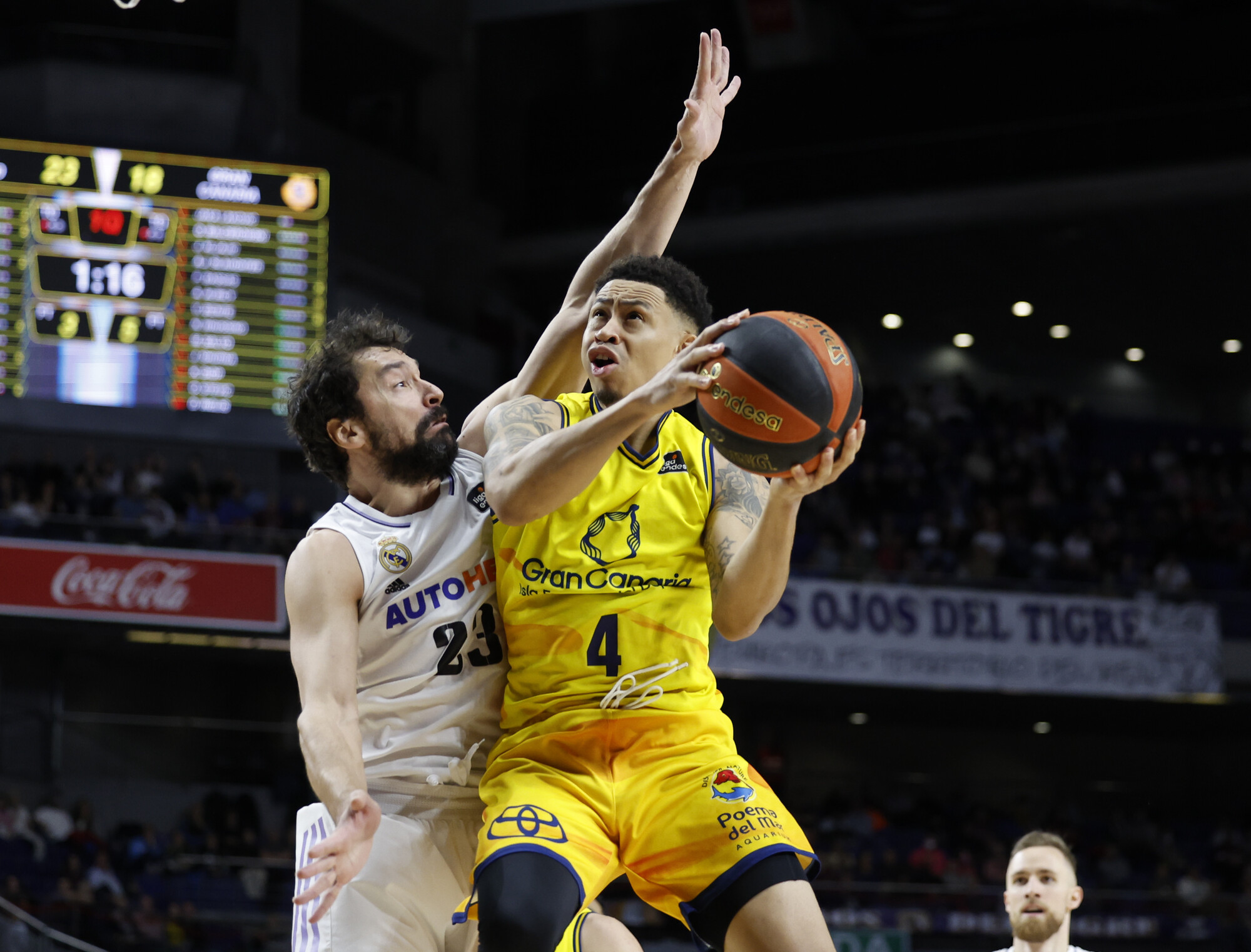 Jugador del Gran Canaria intenta anotar mientras es defendido por un rival del Madrid.