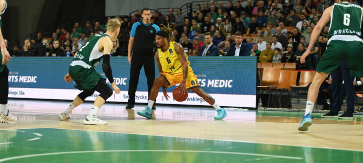 Jugador del Gran Canaria driblando ante dos oponentes del Slask Wroclaw en un partido.