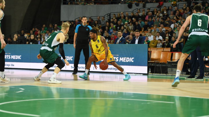 Jugador del Gran Canaria driblando ante dos oponentes del Slask Wroclaw en un partido.