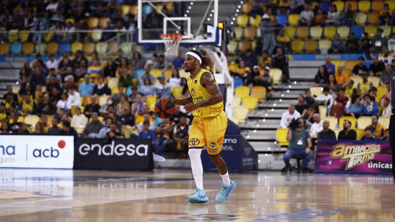 Jugador del Gran Canaria driblando el balón en un partido con público en las gradas.