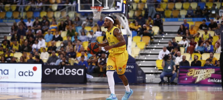 Jugador del Gran Canaria driblando el balón en un partido con público en las gradas.