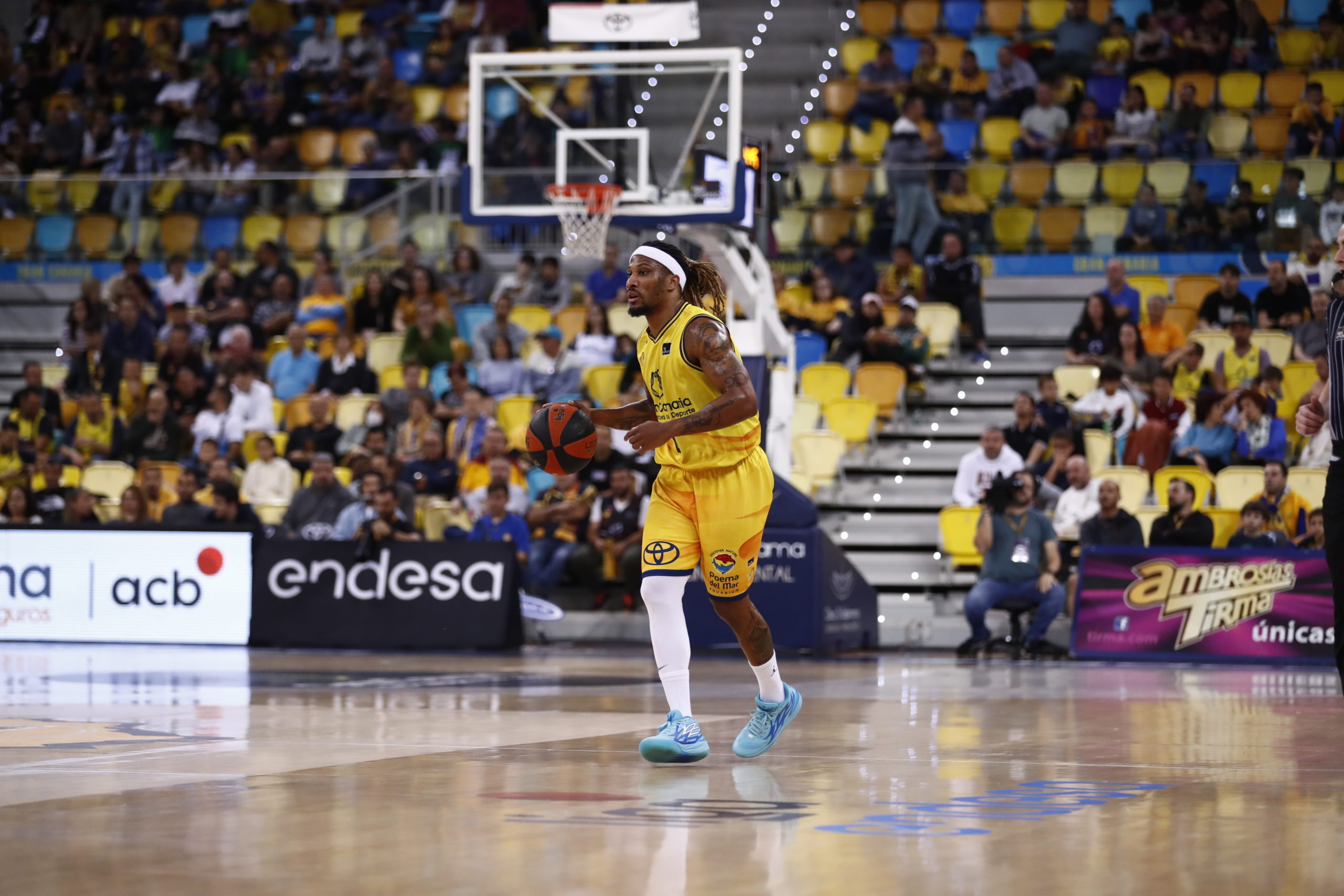 Jugador del Gran Canaria driblando el balón en un partido con público en las gradas.