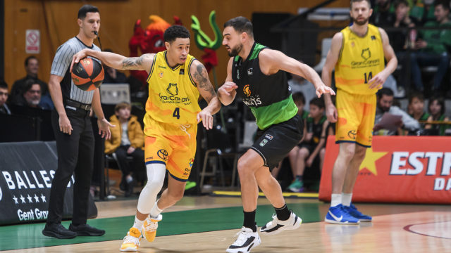 Jugadores de baloncesto en acción durante un partido, el equipo amarillo controla el balón.