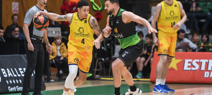 Jugadores de baloncesto en acción durante un partido, el equipo amarillo controla el balón.