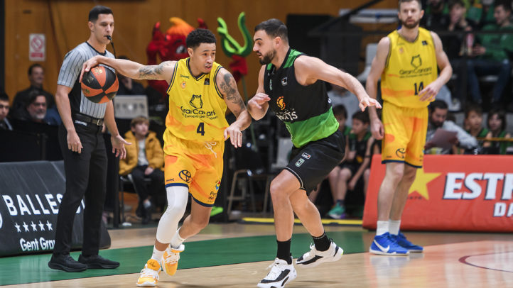 Jugadores de baloncesto en acción durante un partido, el equipo amarillo controla el balón.