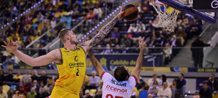 Jugadores en acción durante un partido de baloncesto con un lanzamiento al aro.