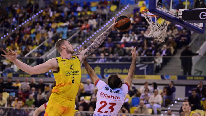 Jugadores en acción durante un partido de baloncesto con un lanzamiento al aro.