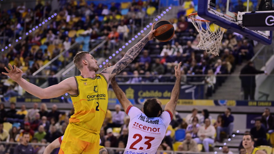 Jugadores en acción durante un partido de baloncesto con un lanzamiento al aro.