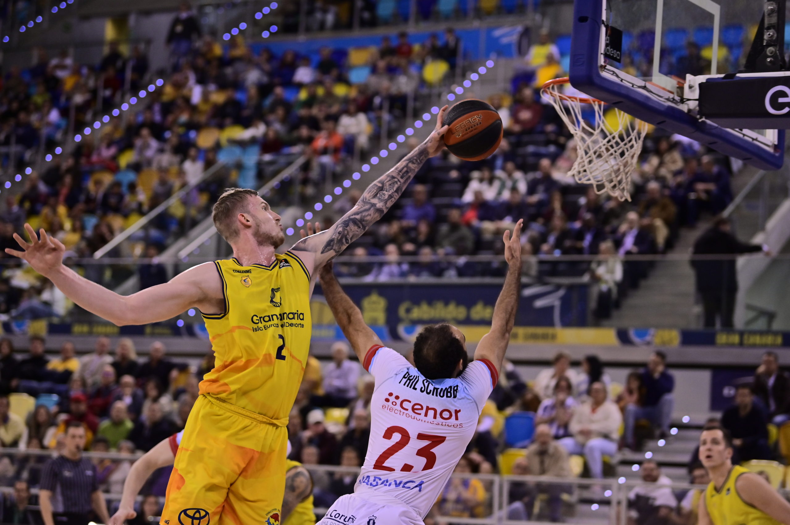 Jugadores en acción durante un partido de baloncesto con un lanzamiento al aro.