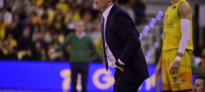 Entrenador Jaka Lakovic dirigiendo al equipo durante un partido, con jugadores de fondo.