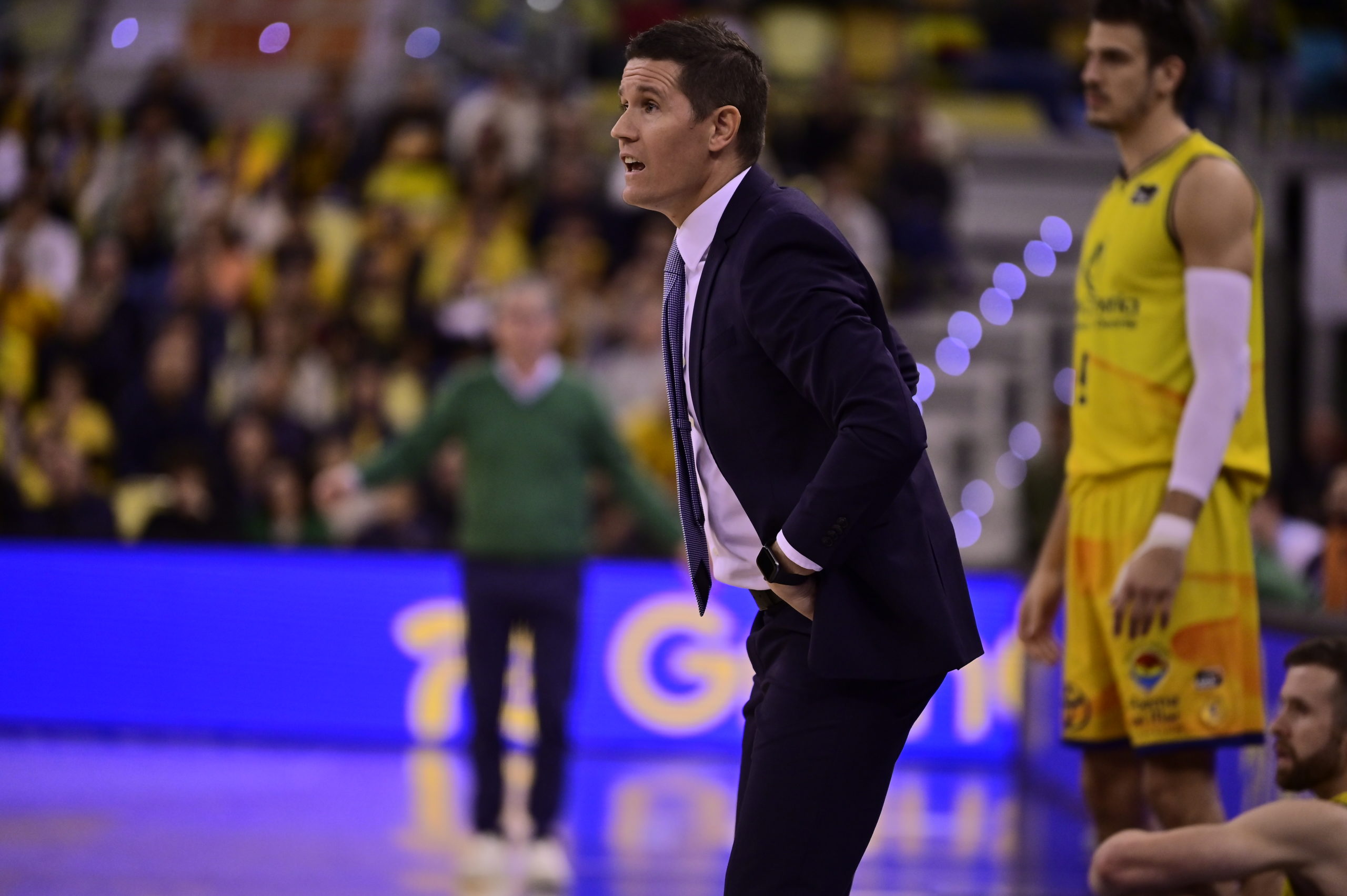 Entrenador Jaka Lakovic dirigiendo al equipo durante un partido, con jugadores de fondo.