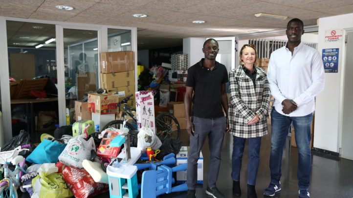 Tres personas posan junto a donaciones para la campaña solidaria Senegal y Gambia.