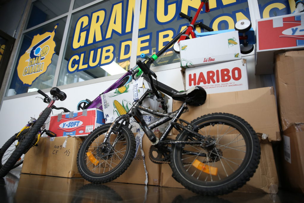 Bicicletas y cajas apiladas en el Club Baloncesto Gran Canaria en un evento colaborativo.