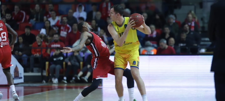 Jugador con balón en acción durante un partido de baloncesto, defendido por otro jugador.