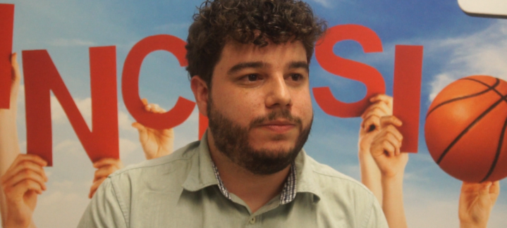 docente del IES Jerónimo Saavedra: ""Con el Proyecto Suma, los alumnos son felices""",Docente del IES Jerónimo Saavedra frente a un cartel sobre inclusión y baloncesto.