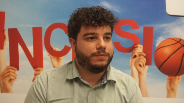 docente del IES Jerónimo Saavedra: ""Con el Proyecto Suma, los alumnos son felices""",Docente del IES Jerónimo Saavedra frente a un cartel sobre inclusión y baloncesto.
