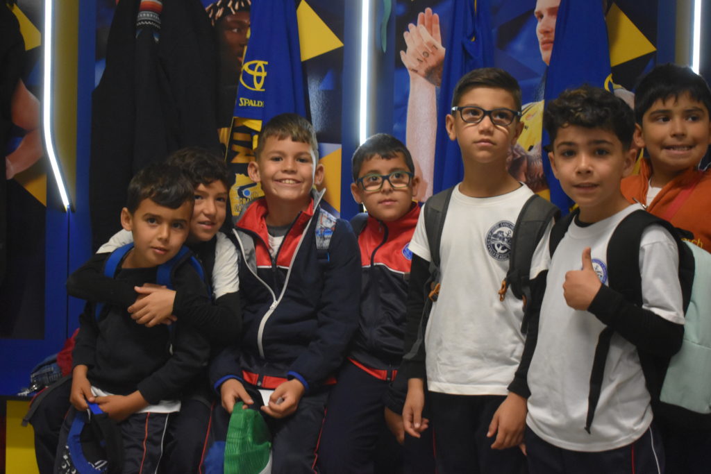 Grupo de niños en una visita al entrenamiento del Gran Canaria, sonriendo y posando.