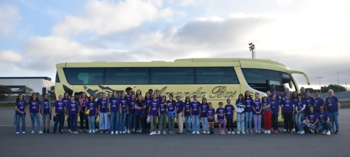 presente en la manifestación del 8M",Grupo de personas con camisetas moradas frente a un autobús amarillo.