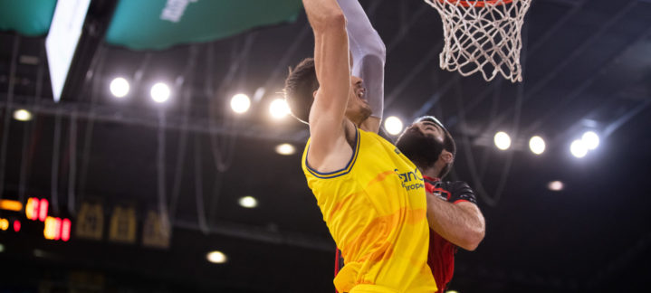Jugador attempting a slam dunk while being challenged by a defender during a match.