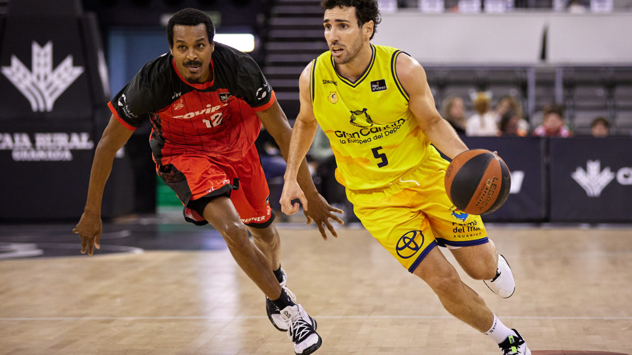Jugador del Gran Canaria avanza con el balón, perseguido por un rival del Covirán Granada.