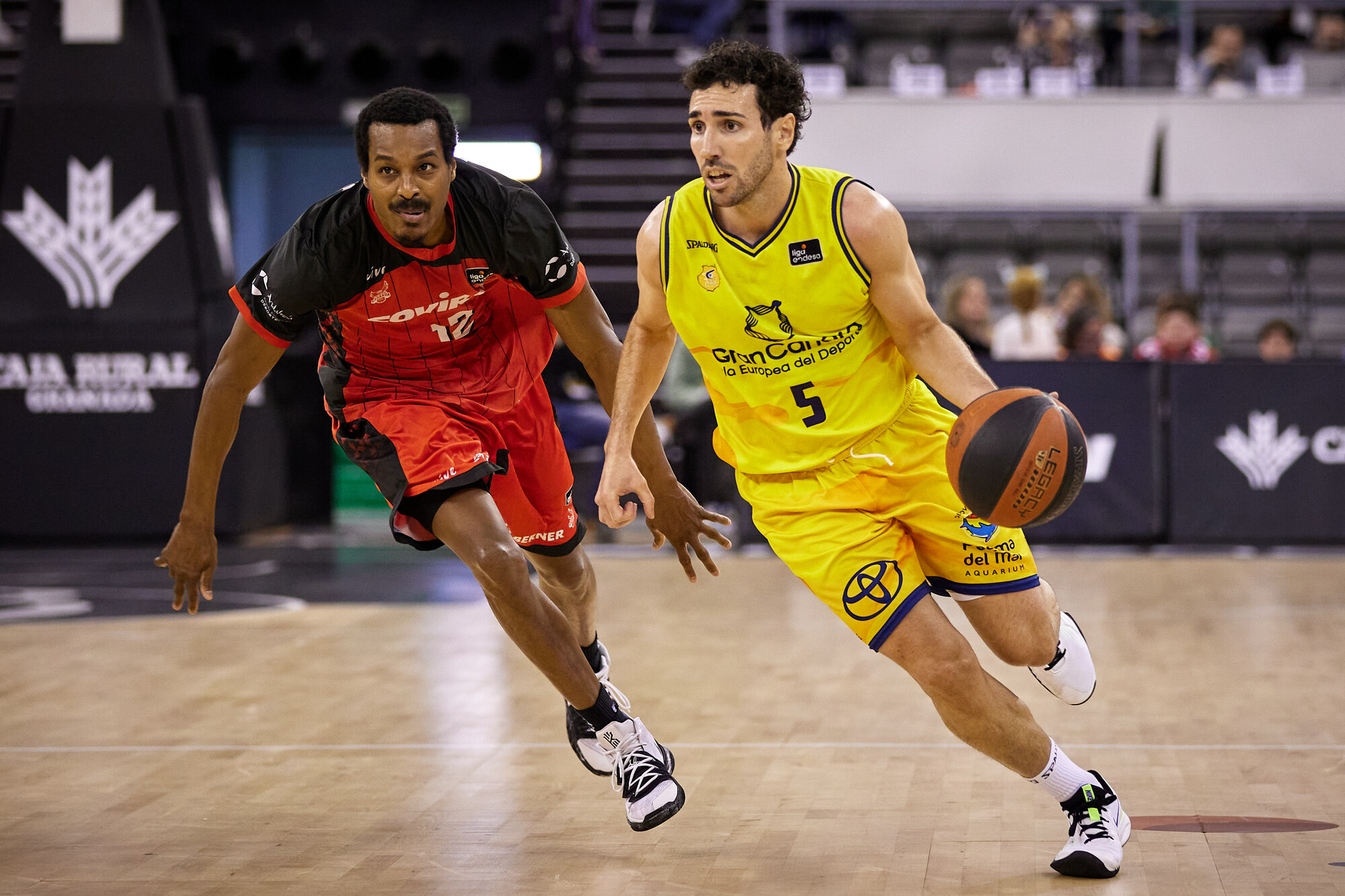 Jugador del Gran Canaria avanza con el balón, perseguido por un rival del Covirán Granada.