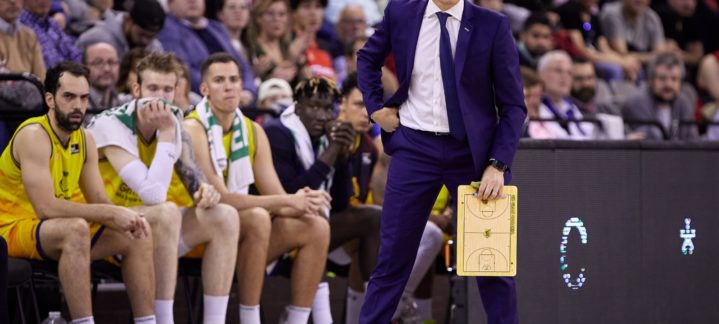 Entrenador Jaka Lakovic dirige desde la banda, rodeado de jugadores en el banquillo.