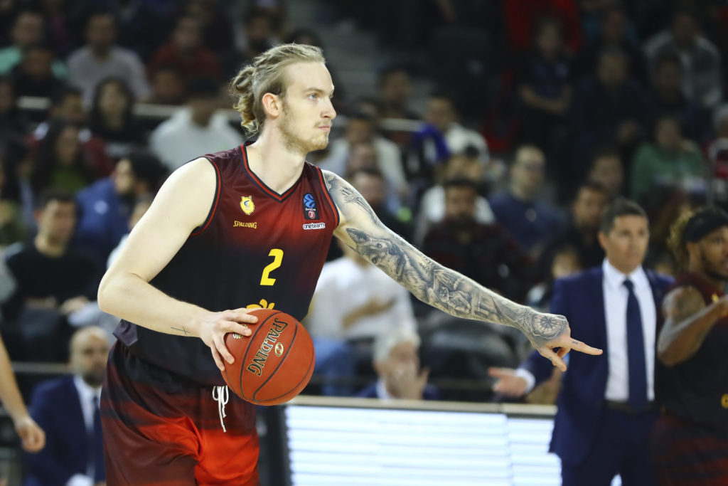 Jugador de baloncesto del Gran Canaria con balón, señalando a su equipo durante un partido.