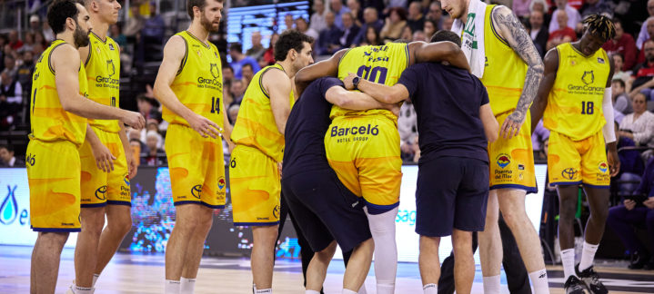lesionado en el choque ante Covirán Granada",Jugadores del Gran Canaria rodean a un compañero lesionado durante un partido.