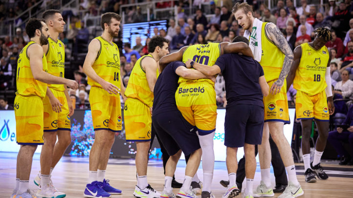 lesionado en el choque ante Covirán Granada",Jugadores del Gran Canaria rodean a un compañero lesionado durante un partido.