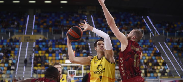 Jugador del Gran Canaria lanzando a canasta mientras es defendido por un jugador del UCAM Murcia.