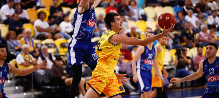 Jugador del Gran Canaria intenta anotar mientras es defendido por un rival en un partido.