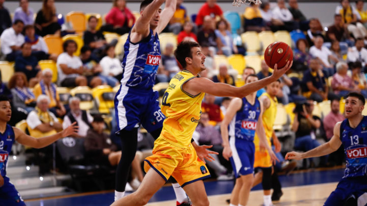 Jugador del Gran Canaria intenta anotar mientras es defendido por un rival en un partido.
