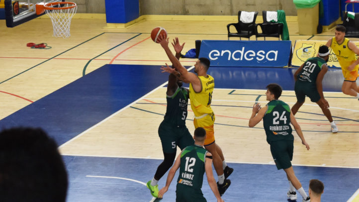Jugadores de baloncesto en acción, uno lanzando a canasta y otros en defensa.