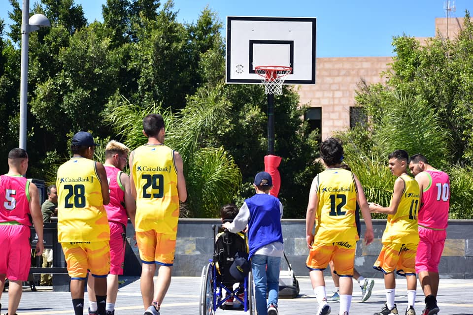 Jugadores de baloncesto con uniformes amarillos y rosa en un evento inclusivo.