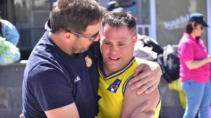Dos personas se abrazan con alegría en un evento de baloncesto inclusivo.