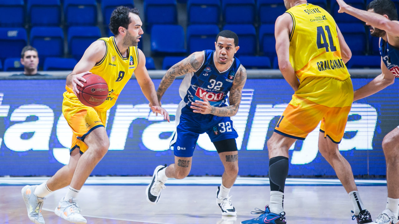 Jugadores en acción durante un partido de baloncesto, con un jugador driblando.
