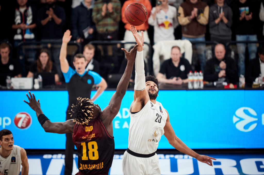 Jugadores compiten por un rebote en un emocionante partido de baloncesto.
