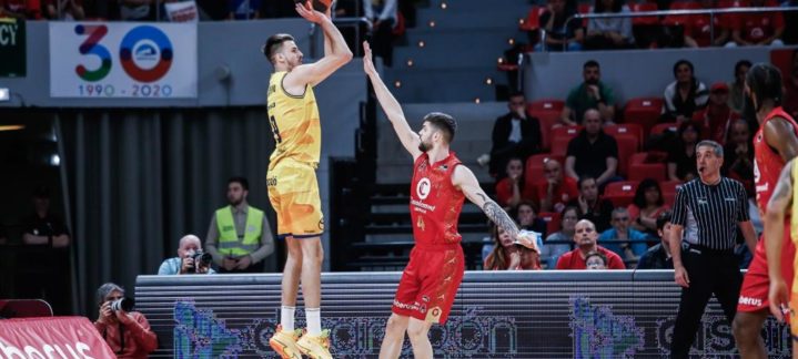 Jugador del Gran Canaria lanzando a canasta mientras es defendido por un rival.