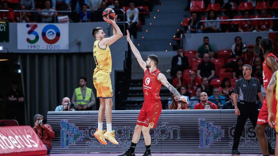Jugador del Gran Canaria lanzando a canasta mientras es defendido por un rival.