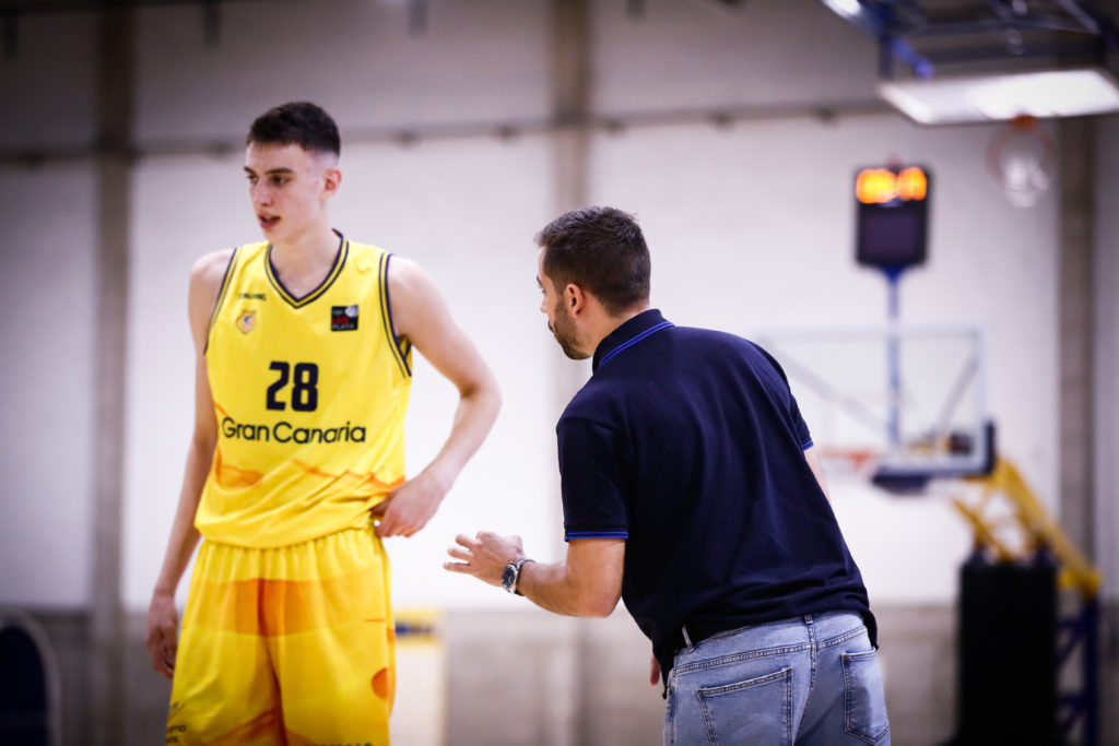 Jugador del Gran Canaria escucha instrucciones de su entrenador en una práctica de baloncesto.