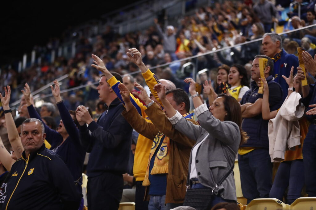  a por el primer paso hacia el título","Aficionados del Gran Canaria animando en un evento deportivo, mostrando apoyo al equipo.