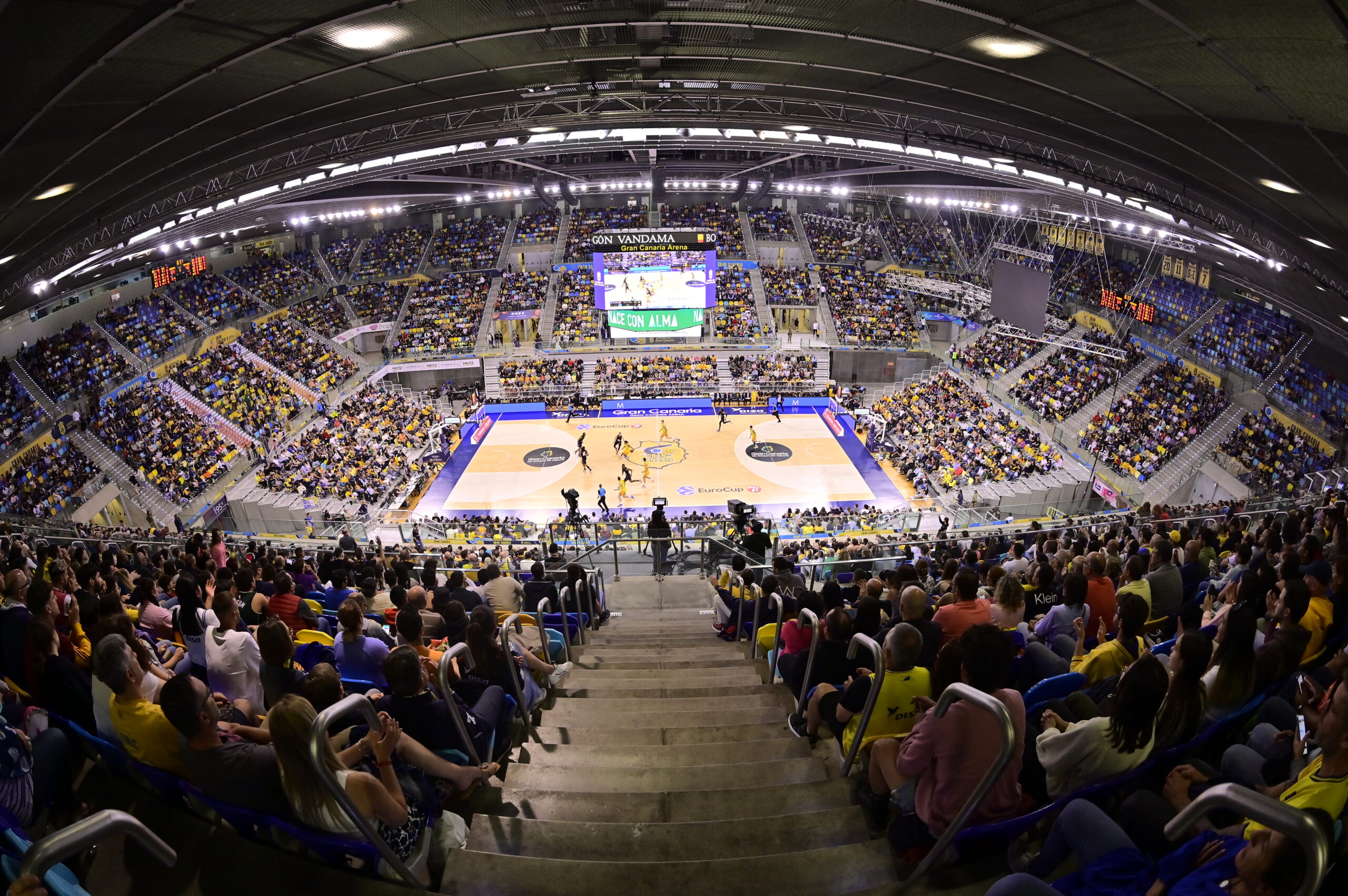 Aficionados disfrutan de un partido de baloncesto en el Gran Canaria Arena llenando las gradas.