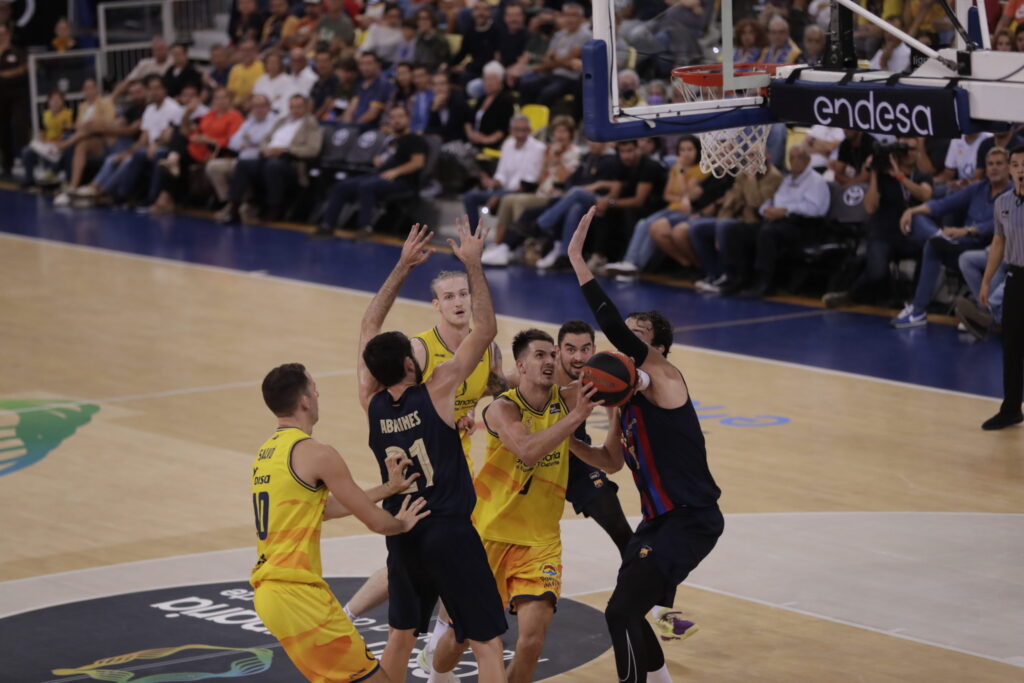 Jugadores compiten por el balón en un partido de baloncesto en el Palau Blaugrana.